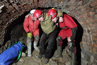 Volunteer casualty Chris Halliwell (from 605 Auxiliary Squadron (Cosford)) being helped out the tunnel.
