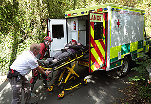 Loading the stretcher into the Red Cross ambulance.