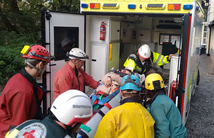 Loading the stretcher into the Red Cross ambulance.